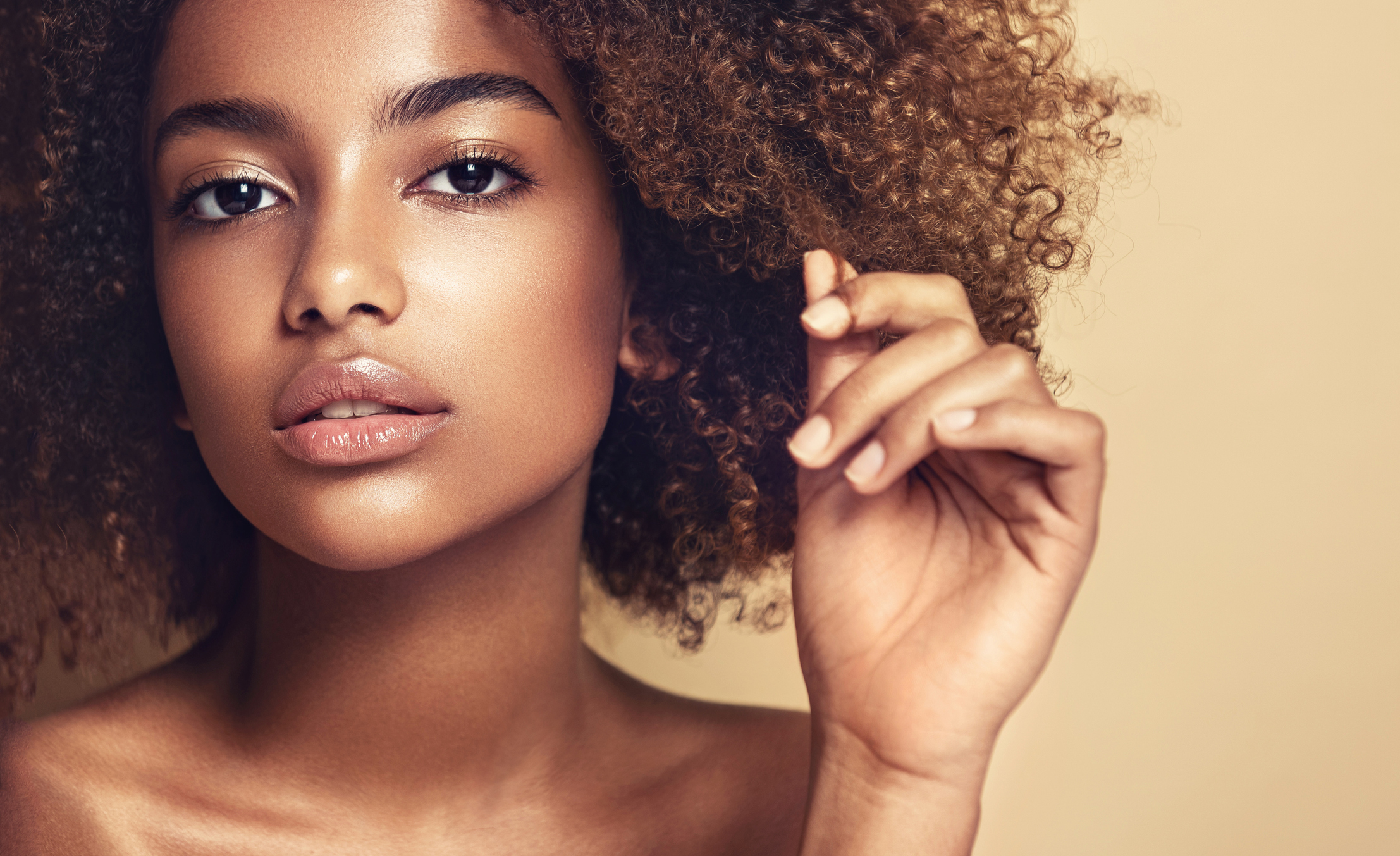 Close-up portrait of young woman with thoughtful and sincere look at viewer. Hairdressing art, natural Afro hair.