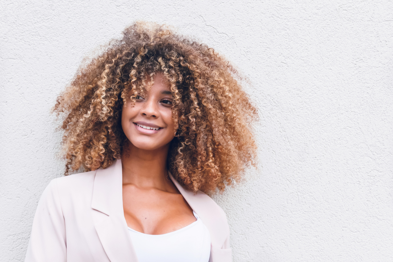 face of beautiful afro woman with curly hair on white wall background